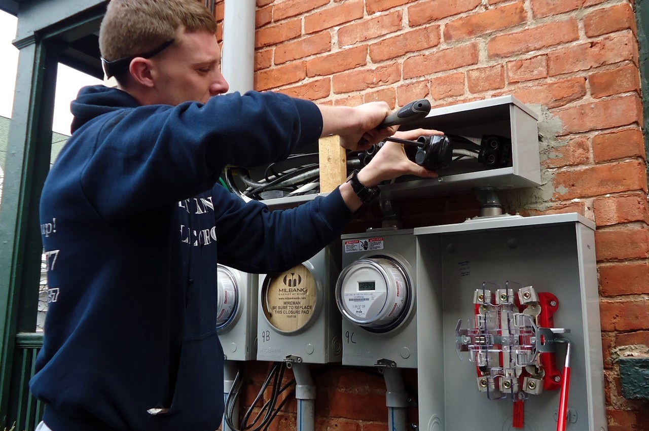 Electrician upgrading outdoor meter connections on a multifamily residential building